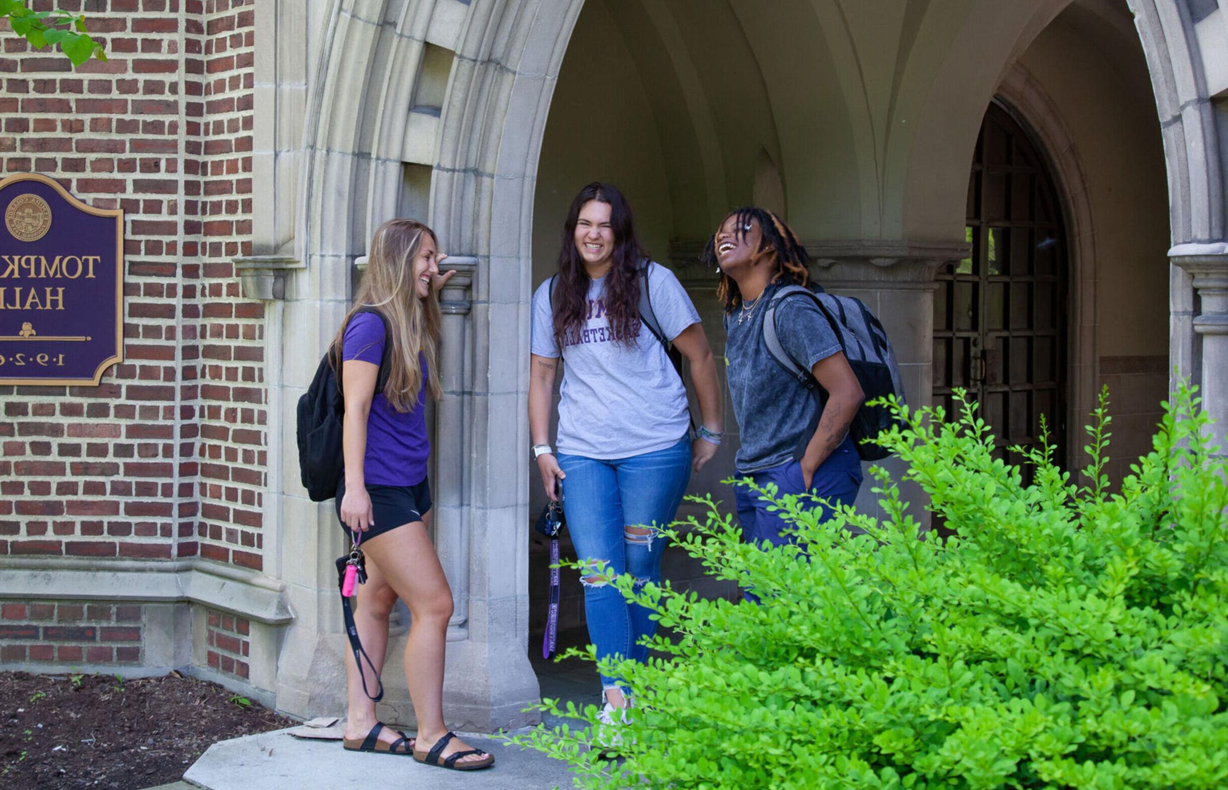 三名女学生在汤普金斯大厅门口闲逛时大笑